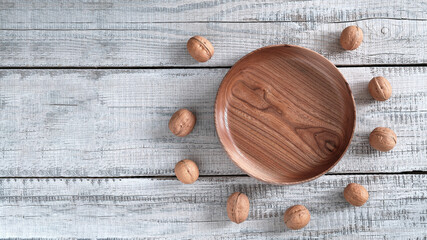Fototapeta na wymiar On a wooden background - a platter of elm wood, and around it are many walnuts