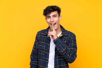 Young Argentinian man over isolated yellow background doing silence gesture