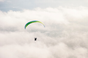 The paraglider flies above the clouds against the backdrop of the city. View from the mountain
