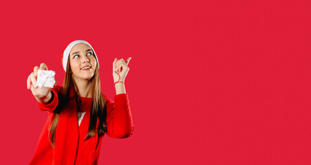 Banner. Girl holds a gift box and points up with a finger. Red background with space for your advertisment.