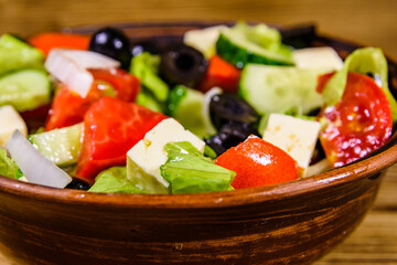 Ceramic plate with greek salad on wooden table