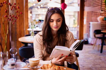 Attractive woman sitting in the cafe and reading book