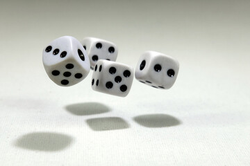  White playing dice cubes in motion on the white canvass surface