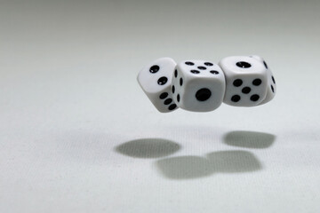  White playing dice cubes in motion on the white canvass surface