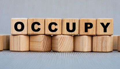 OCCUPY - word on wooden cubes on a beautiful gray background