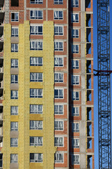 Fototapeta na wymiar A construction crane is installed next to a multi-storey building under construction