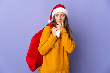 Lithianian woman with christmas hat isolated on purple background having doubts
