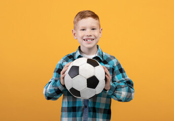 Boy posing with soccer ball on yellow studio background