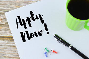 Top view of pen, pinboards, a cup of coffee and white paper on a white background written with text APPLY NOW. Business and education concept. 