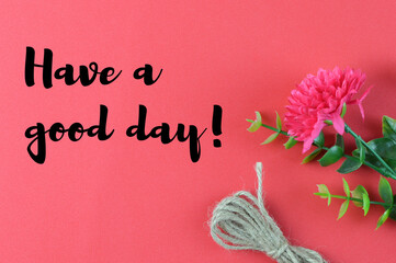 Fototapeta premium Top view of flower, rope on a red background written with text HAVE A GOOD DAY!. Motivational concept. 