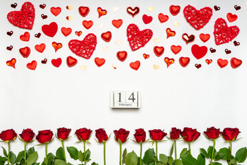 Fresh red rose flowers, hearts and sweets on white background. Calendar date February 14, floral composition, greeting card for Valentine's day. Love and romance concept. Flat lay, top view