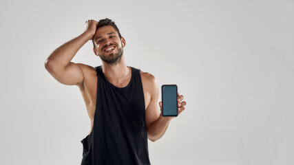 Young handsome caucasian trained man holding smartphone