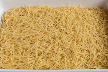 A ceramic plate filled with noodles on a wooden table. Organic textures as a background. Vegan food and vermicelli soups.