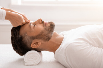 Bearded man having relaxing head massage at spa