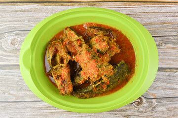 Spicy catfish delicious food and favorite food in a green bowl isolated on a wooden background. Famous food among Malaysian.
