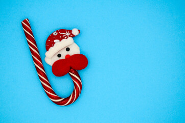 Santa and candy cane on blue background with copy space. Creative Christmas concept.