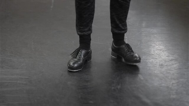 Single male tap dancer wearing black trousers and leather shoes dancing simple irish dance.