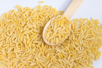 raw risoni in a wooden spoon