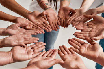 Diverse women holding their hands open palm together, making a circle over grey background. Concept of support, racial unity and relations in society