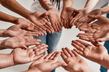 Diverse women holding their hands open palm together, making a circle over grey background. Concept...