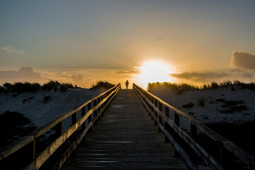 Silhouette of a woman at the top of a wooden path during a sunset
