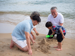Happy multi-generation Asian family having fun in the sea on a beach holiday...