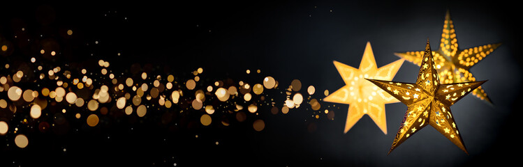 Ornamental gold star lanterns for Christmas on black background with golden bokeh stardust, extra...