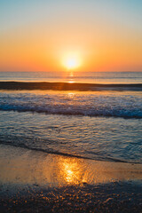 Fototapeta na wymiar Beautiful summer sunset at the beach, waves and sand
