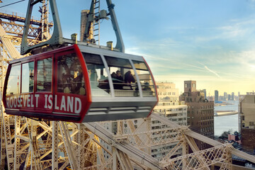 New York, USA - December 24, 2019: Cabin of the famous Roosevelt Island cable car in front of the Ed Coch Queensboro Bridge from Manhattan to Queens in New York. - obrazy, fototapety, plakaty