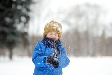 Little boy having fun playing with fresh snow. Snowball fight. Active outdoors leisure for child in snowy winter day.