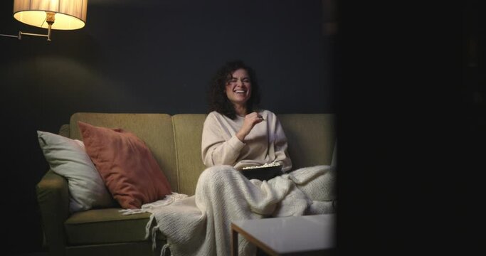 The girl is watching a comedy on TV. To watch series. The girl on the couch with popcorn is watching a movie. 4k slow motion video