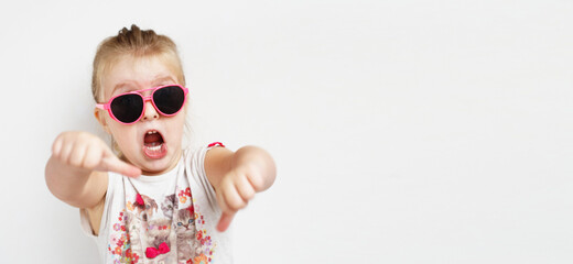 Child in pink sunglasses making funny face. positive girl shouts on a white background