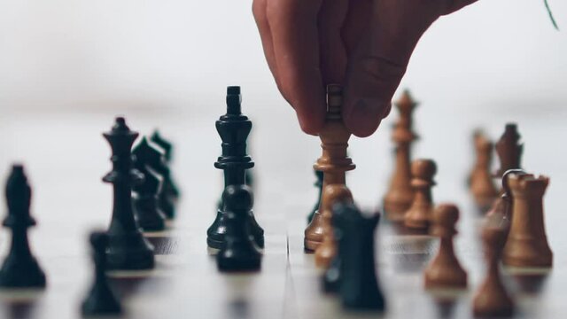 Slow motion shot of a white king chess piece knocking over the black king chess piece, defeating the black team.