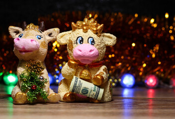 Bull and cow toys on a dark background with light bulbs. New year's background.