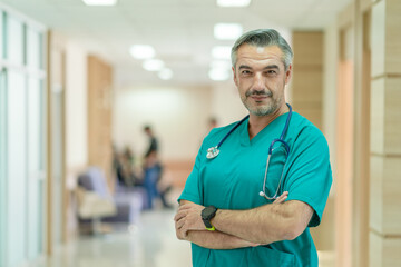 Portrait of senior doctor with crossed arms standing in hospital