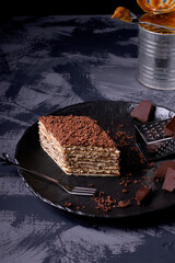 Mikado cake with caramel and chocolate buttercream on the black ceramic plate. Armenian cuisine dessert