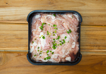 fresh raw pork belly beef sliced on square plate isolated on wooden background, shabu, hot pot ingredients