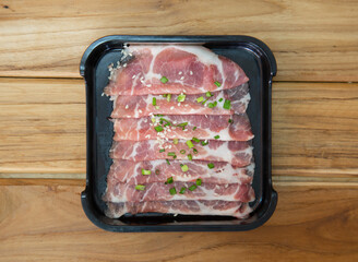 fresh raw pork belly beef sliced on square plate isolated on wooden background, shabu, hot pot ingredients
