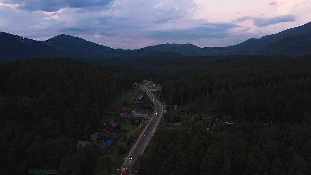 Night road along the forest, shooting from a height. Twilight
