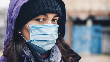New real life during pandemic. Young woman in medical mask outdoors, to protected from corona virus.