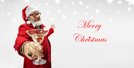 Fototapeta na wymiar Greeting flyer for ad. Concept of Christmas, 2021 New Year's party, winter mood, holidays. Copyspace, postcard. Santa Claus in stylish outfit proposing champagne on white background. Merry Christmas