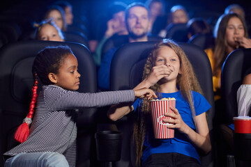 Multiracial friends enjoying cartoon in cinema hall.