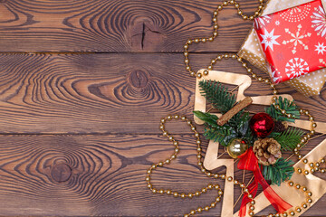 Metallic golden fir tree with branches and cones, Christmas decorations, beads and gifts wrapped in paper on a wooden table. Flat lay, copy space.