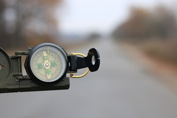Classic navigation compass on background of road as symbol of tourism with compass, travel with...