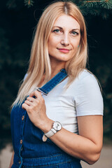 Close-up portrait of blue eyed blonde woman in jeans with suspenders