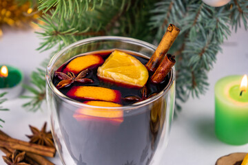 Hot mulled wine with red wine, orange, cinnamon sticks and star anise. Cosy Christmas decoration with candles on white background