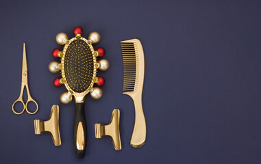 Fototapeta premium New year's banner with hairdressing tools in gold on a dark blue background. The comb is decorated with Christmas balls. Greeting card, template with accessories for hair salon and space for text.