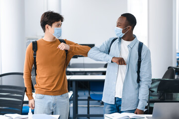 Obraz premium Multiracial students wearing face masks greeting and bumping elbows