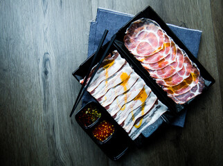 fresh raw pork, meat ,beef, belly, sliced on square plate  on fabric and wood, wooden background, shabu, hot pot ingredients.