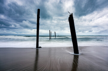 Big wave hitting a decay wooden bridge on the beach in stormy weather at Pilai beach, Phang nga